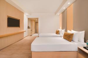 twee bedden in een hotelkamer met een televisie bij Lemon Tree Hotel, Haridwar in Haridwār