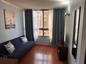uma sala de estar com um sofá azul e uma janela em Apartamentos Orquídea Suite em Santiago