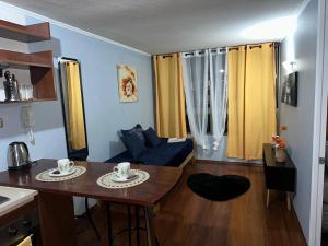 pequeña sala de estar con mesa y cocina en Apartamentos Orquídea Suite, en Santiago