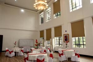 Habitación grande con mesas blancas y sillas con arcos rojos en Isla De Oro Hotel, en Mamburao