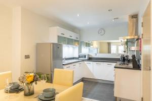 una cucina con armadi bianchi e tavolo con sedie di Cotels at Centro Serviced Apartments a Northampton