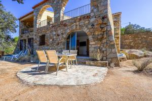 une maison en pierre avec une table et des chaises dans l'établissement Belle Vue de Fogata, à Corbara