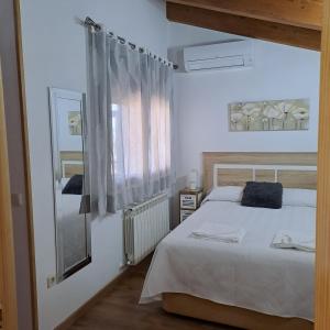 a bedroom with a white bed and a mirror at El Mondalindo, Acogedor apartamento mirador in Lozoyuela