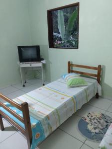 um quarto com uma cama e uma mesa com uma televisão em Apartamento em Chácara Aconchegante em Angra dos Reis