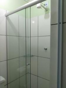 La salle de bains est pourvue d'une porte de douche en verre. dans l'établissement Apartamento em Chácara Aconchegante, à Angra dos Reis
