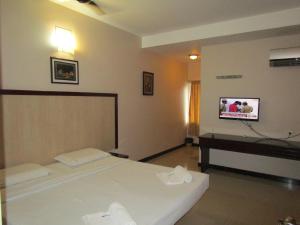 a bedroom with a bed and a tv on the wall at Hotel Subam in Palni