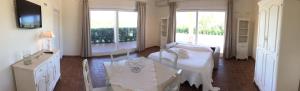 a white room with a table and two windows at Relais Le Fornacelle in Castagneto Carducci