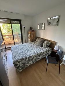 ein Schlafzimmer mit einem Bett und einem großen Fenster in der Unterkunft Appartement agréable 1 chambre in Mérignac