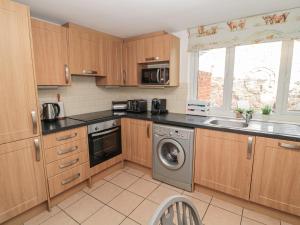 cocina con armarios de madera, fregadero y lavavajillas en 2 Cross View en Berwick-Upon-Tweed