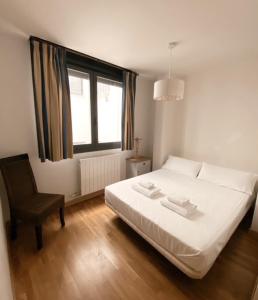 a bedroom with a bed and a chair and a window at Apartamentos Laurel in Logroño
