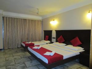 a bedroom with two beds with red and white sheets at Hotel Subam in Palni