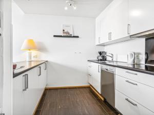 a kitchen with white cabinets and a wooden floor at Apartment Kimi - 100m from the sea in Western Jutland by Interhome in Havneby