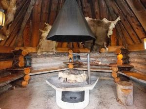 een kachel in een blokhut met een zwarte bel bij Holiday Home Kelopirtti a by Interhome in Saariselkä