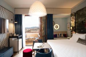 フィレンツェにあるホテルロンドラ フィレンツェのベッド、テーブル、椅子が備わるホテルルームです。