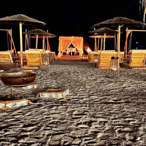 Alia Luxury Suites and Spa في شاراكي: مجموعة من الكراسي والمظلات على الشاطئ في الليل
