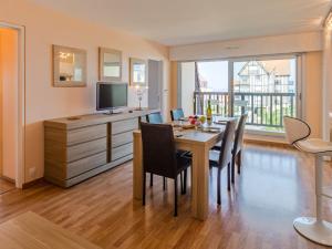 a dining room with a table with chairs and a television at Apartment Cap Cabourg-31 by Interhome in Cabourg