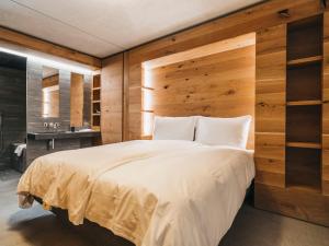1 dormitorio con 1 cama grande y pared de madera en Apartment rocksresort-8 by Interhome, en Laax