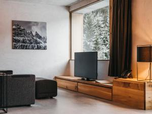sala de estar con TV y ventana en Apartment rocksresort-8 by Interhome, en Laax