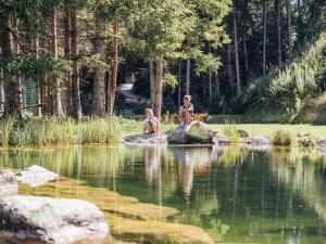 two people sitting on rocks near a body of water at Apartment Theo by Interhome in Stams