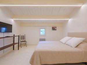a white bedroom with a bed and a television at Holiday Home Malanuit by Interhome in Bauduen