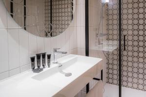 bagno bianco con lavandino e specchio di Hotel Indigo Florence, an IHG Hotel a Firenze