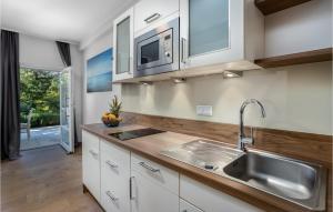 una cocina con armarios blancos y fregadero en Amazing Apartment In Crikvenica With Outdoor Swimming Pool, en Crikvenica