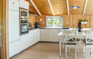 Sindrupにある2 Bedroom Gorgeous Home In Hurup Thyの白いキャビネット、テーブルと椅子付きのキッチンが備わります。
