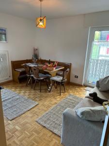 - un salon avec une table, des chaises et un canapé dans l'établissement COSTALUNGAHOUSE TrekkingBikeSki selfcheck-in apartment, à Carezza al Lago