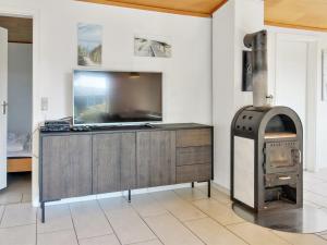 uma sala de estar com uma televisão e um fogão a lenha em Holiday Home Nalin - 500m from the sea in Western Jutland by Interhome em Lakolk