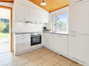 uma cozinha com armários brancos e uma janela em Holiday Home Nalin - 500m from the sea in Western Jutland by Interhome em Lakolk