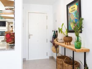Un pasillo con una puerta blanca y una mesa con cestas. en Apartment Maroma by Interhome, en Torre del Mar