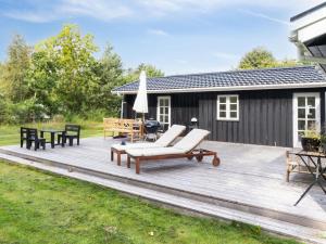 una terraza de madera con tumbonas y sombrilla en Holiday Home Mella - 625m from the sea in Sealand by Interhome, en Højby