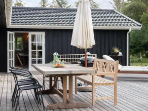 una mesa de madera con sombrilla y sillas en una terraza en Holiday Home Mella - 625m from the sea in Sealand by Interhome, en Højby