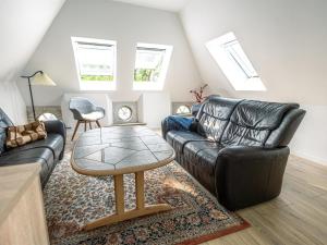 een woonkamer met een zwarte leren bank en een tafel bij Holiday Home Arnora - 48km from the sea in Western Jutland by Interhome in Højer