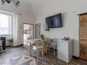 een eetkamer met een tafel en een tv aan de muur bij Apartment Elisa by Interhome in Imperia