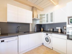 a kitchen with white cabinets and a washer and dryer at Holiday Home Marges by Interhome in Bauduen