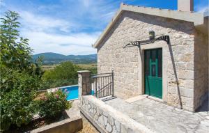 una pequeña casa de piedra con una puerta verde en Awesome Home In Bajagic With Jacuzzi, en Bajagić