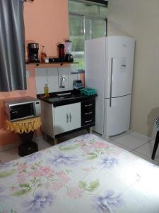 a small kitchen with a refrigerator and a stove at Apartamento em Chácara Aconchegante - Kitnet in Angra dos Reis