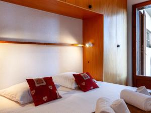 Schlafzimmer mit einem Bett mit roten und weißen Kissen in der Unterkunft Apartment Jasmins by Interhome in Veysonnaz