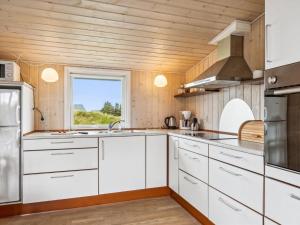 uma cozinha com armários brancos e uma janela em Holiday Home Isabel - 500m from the sea in NW Jutland by Interhome em Torsted