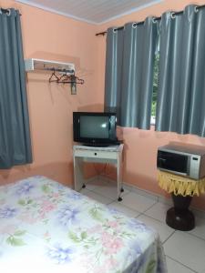 um quarto com uma cama, uma televisão e uma secretária em Apartamento em Chácara Aconchegante em Angra dos Reis