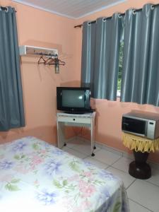 a bedroom with a bed and a tv and a desk at Apartamento em Chácara Aconchegante - Kitnet in Angra dos Reis +63 photos