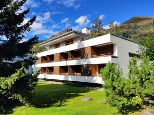 un edificio blanco con árboles delante de él en Apartment Verbena by Interhome, en Davos