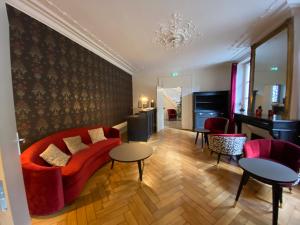 sala de estar con sofá rojo y 2 mesas en Logis HOTEL DU PARC en Pont-à-Mousson
