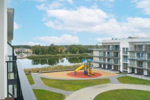 um parque infantil em frente a um edifício com um lago em Lovely SPA 31 em Dziwnów