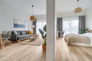 a white bedroom with a bed and a living room at Lovely SPA 31 in Dziwnów +39 photos
