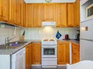 a kitchen with wooden cabinets and a white stove top oven at Holiday Home Lomariekko 6 a 4 pikkuriekko by Interhome in Saariselka