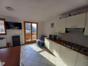 uma cozinha com armários brancos e vista para uma sala de estar em CASA TATA -Appartamento vista mozzafiato em Lizzola Alta