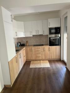 a kitchen with white cabinets and a wooden floor at Downtown Great Apartment in Strumica