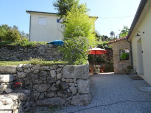 una pared de piedra con dos sombrillas junto a un edificio en A CASA COM 2 PEREIRAS en Terras de Bouro